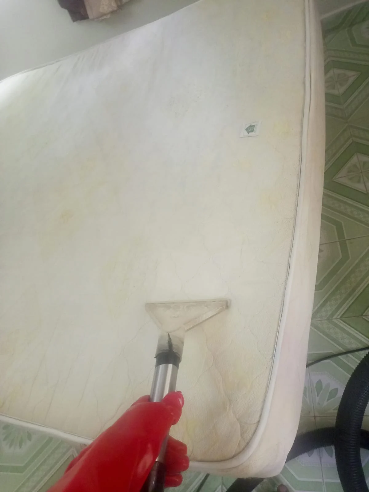 Mattress being deep cleaned with an upholstery extraction tool